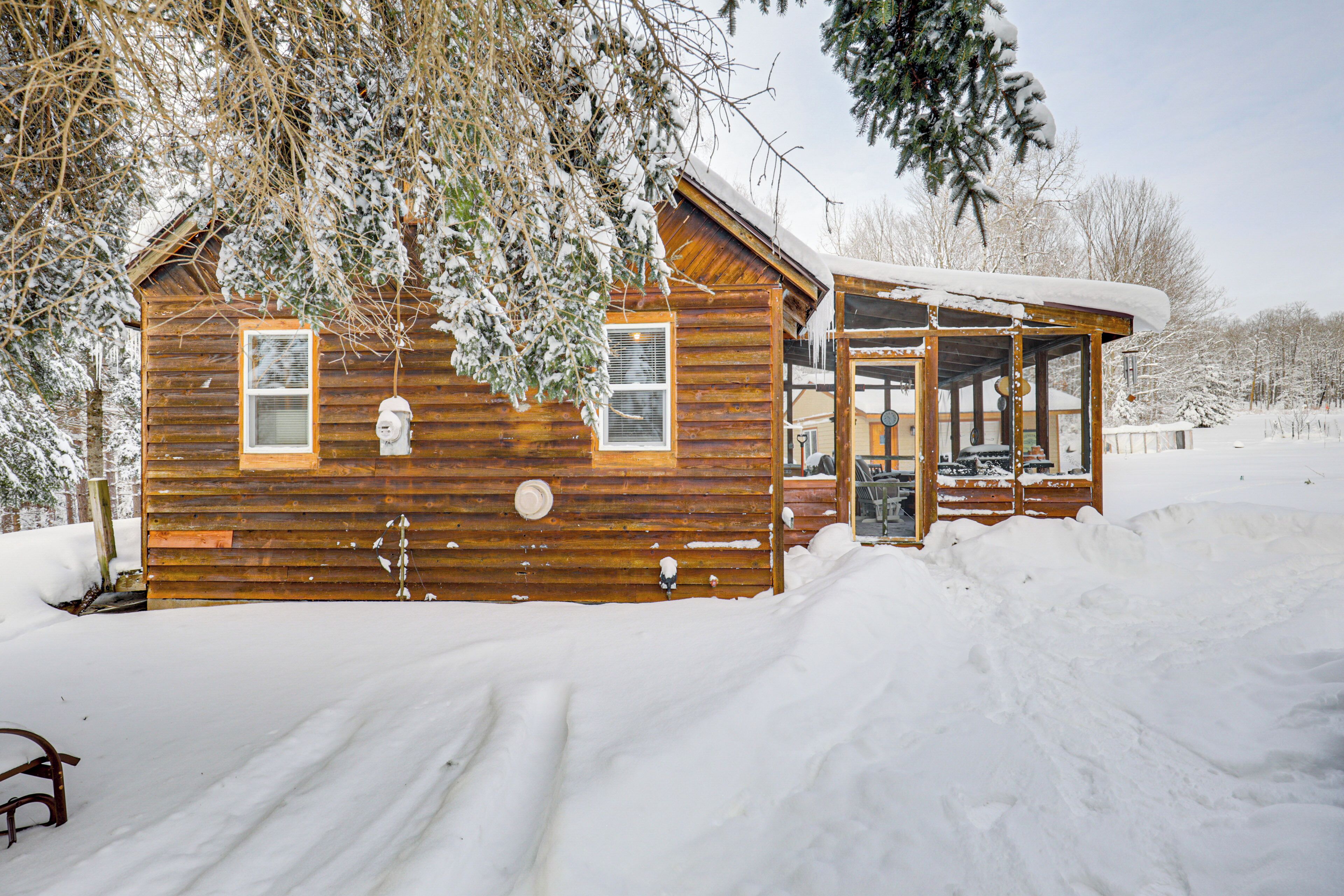 A wooden cabin with a covered porch, surrounded by snow.
