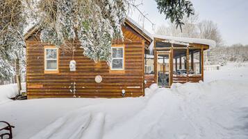 A wooden cabin with a covered porch, surrounded by snow.