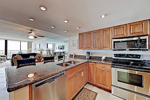 A modern kitchen with wooden cabinets, granite countertops, stainless steel appliances, and a built-in dishwasher. - Resort Condo w/ Gulf Views: Suntide III - Unit 207 (South Padre Island)