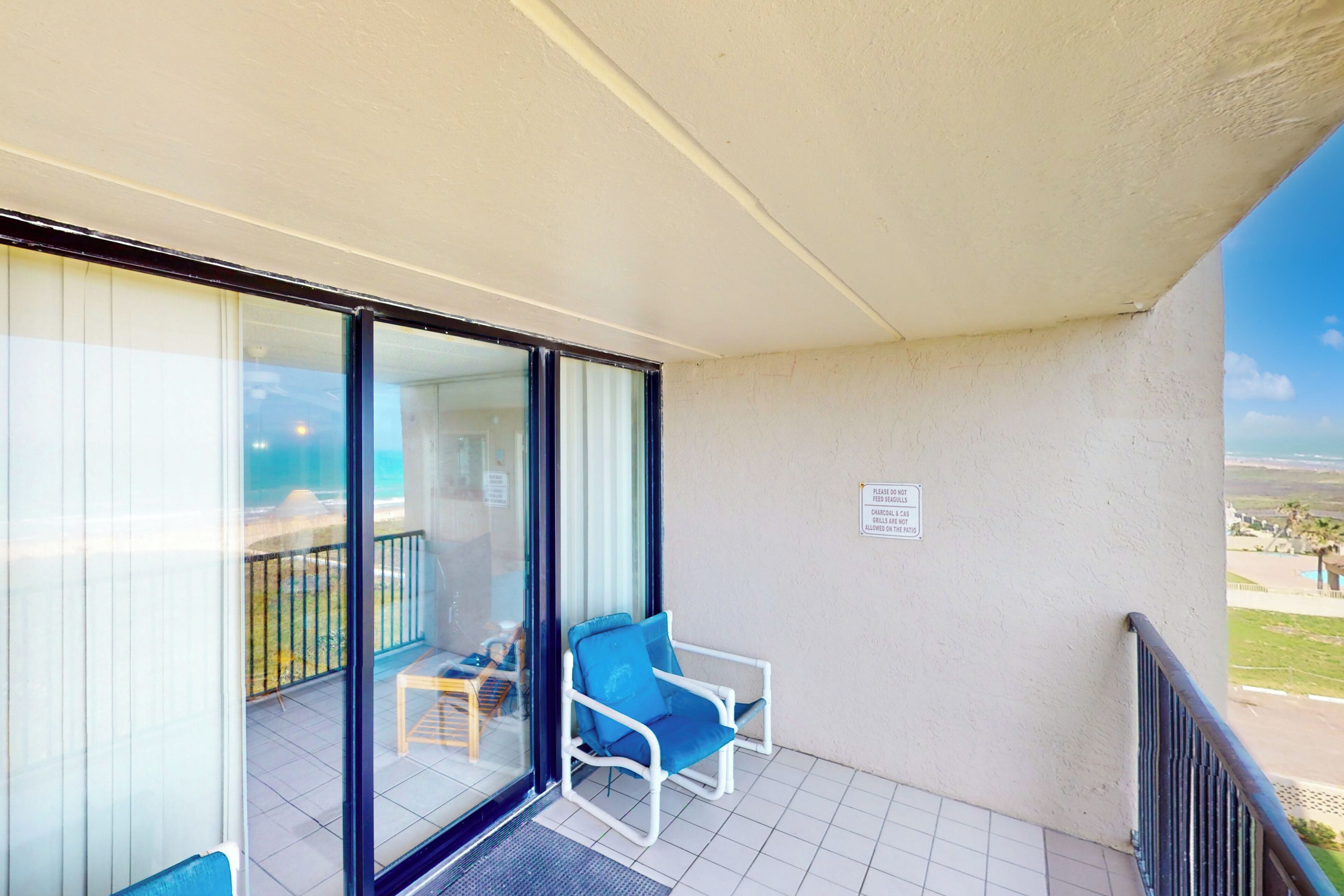 A balcony with a glass door, a blue chair, and a small table.