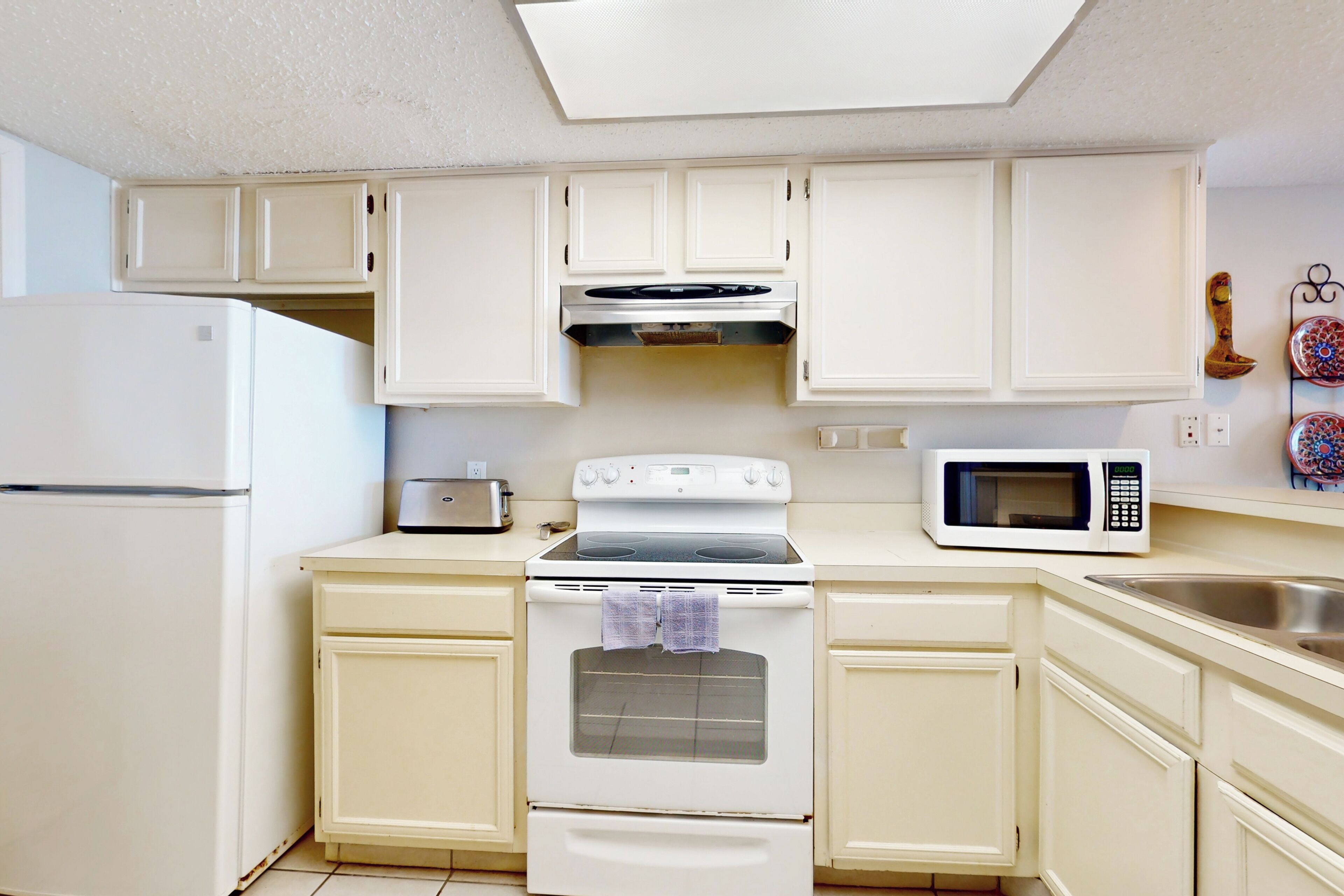 A kitchen with white cabinets, a stove, a microwave, and a refrigerator.