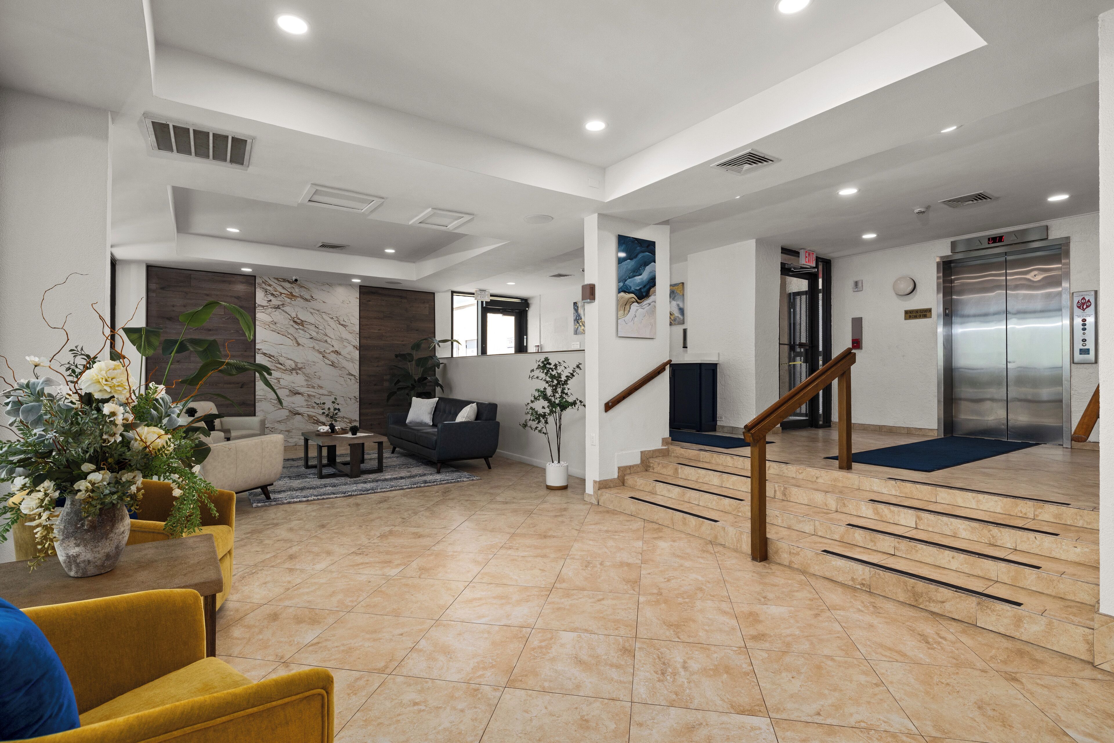 A spacious living area with a sofa, coffee table, and decorative plants.