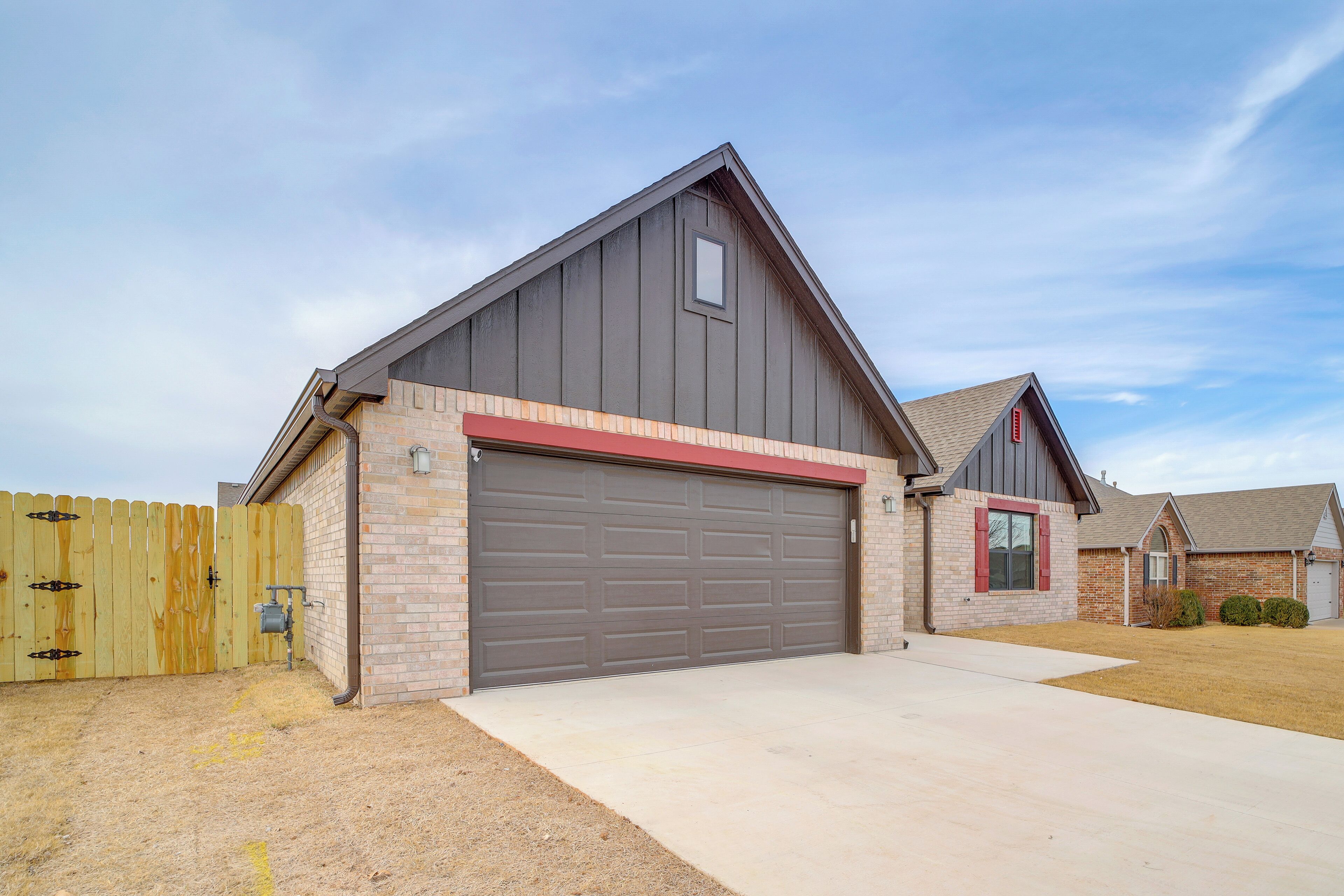 A single-story house with a garage, a wooden fence, and a clear sky.