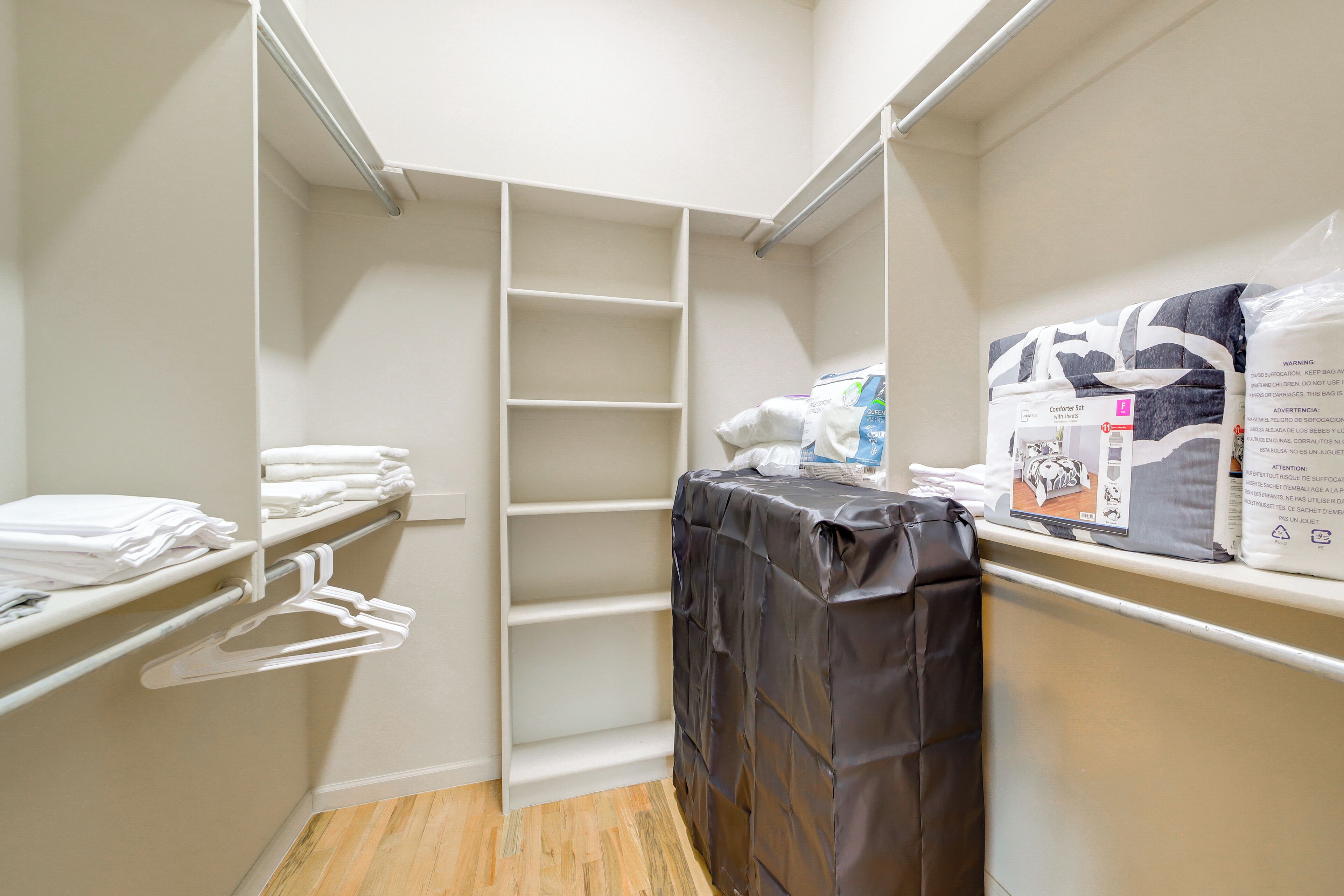 A walk-in closet with shelves, hanging space, and a covered table.