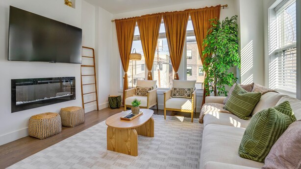 A modern living room with a flat-screen TV, a fireplace, a sofa, and a coffee table. - 5 Mi to Nyc: Bright & Chic Jersey City Getaway! (Jersey City)