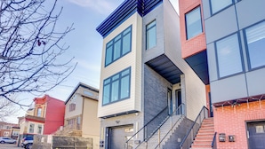 A modern multi-story building with a mix of brick and siding exteriors, large windows, and a visible garage door. - 5 Mi to Nyc: Bright & Chic Jersey City Getaway! (Jersey City)