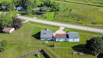 A rural landscape with a road, houses, and a fenced area.