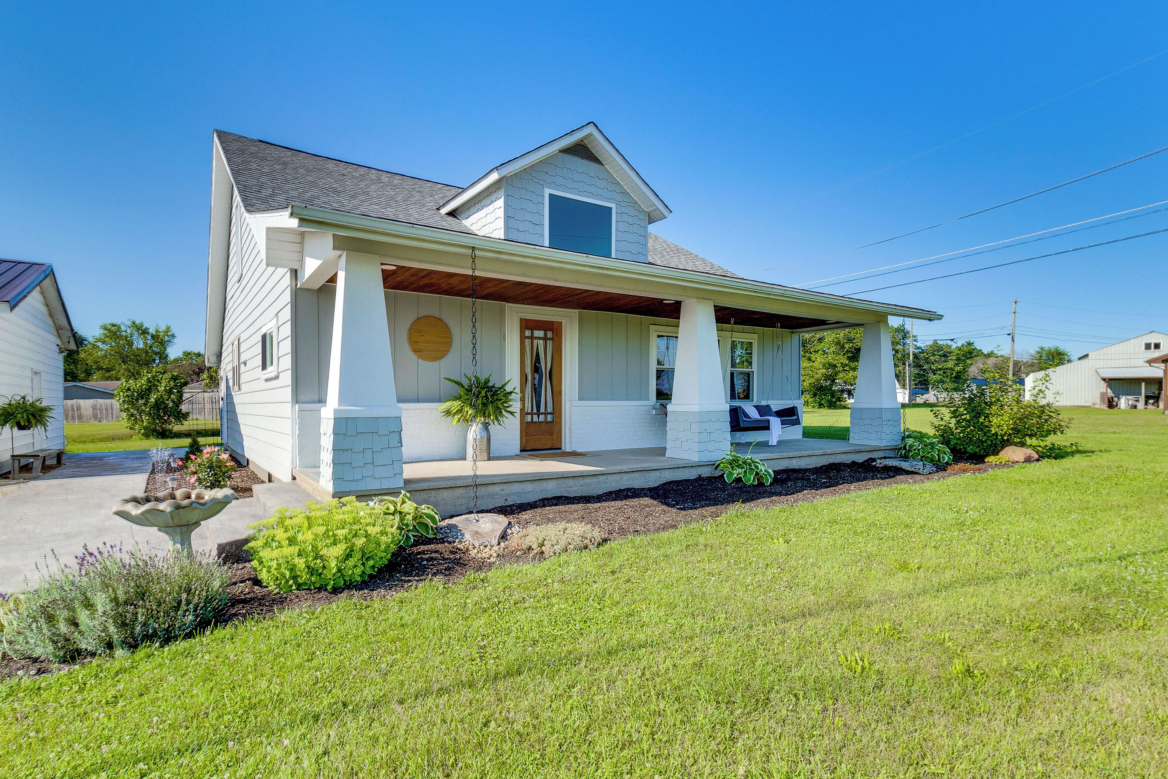 A single-story house with a front porch, a small garden, and a clear blue sky.