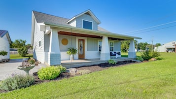 A single-story house with a front porch, a small garden, and a clear blue sky.
