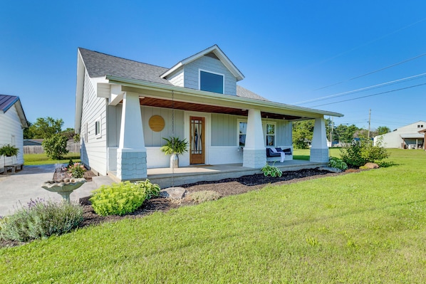 A single-story house with a front porch, a small garden, and a clear blue sky.
