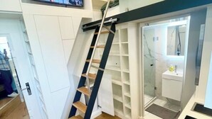 Ein modernes Interieur mit einer Holztreppe, eingebauten Regalen und einer Duschkabine aus Glas.