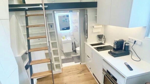 Eine kompakte Küche mit einer Holztreppe, einem kleinen Spülbecken und einer Kaffeemaschine.