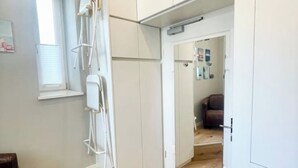 Ein Zimmer mit einem großen Spiegel, der einen Wohnbereich, weiße Schränke und ein Fenster mit Jalousien reflektiert.