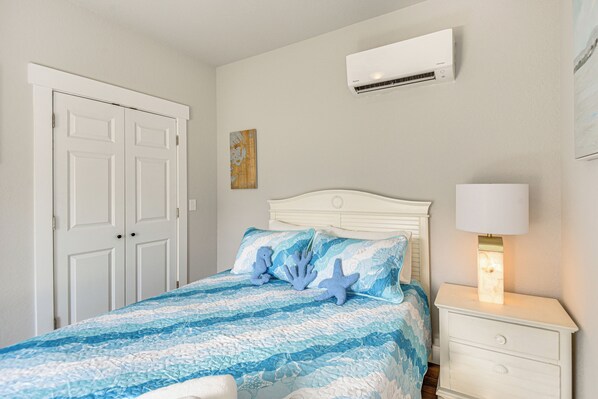 Ein Schlafzimmer mit einem Bett, einem Nachttisch, einer Wand-Klimaanlage und einer Tür.