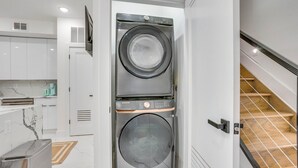 A compact laundry room with a Samsung washer and dryer, a small kitchen area with marble countertops, and a wooden staircase. - 6 Mi to Times Square: Stylish Jersey City Retreat (Jersey City)