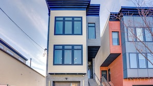 A multi-story building with a modern architectural design, featuring large windows and a combination of brick and siding exteriors. - 6 Mi to Times Square: Stylish Jersey City Retreat (Jersey City)