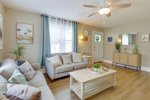 A living room with a sofa, coffee table, and a ceiling fan.