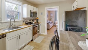 Una cocina moderna con armarios blancos, electrodomésticos de acero inoxidable y una mesa de comedor de madera.