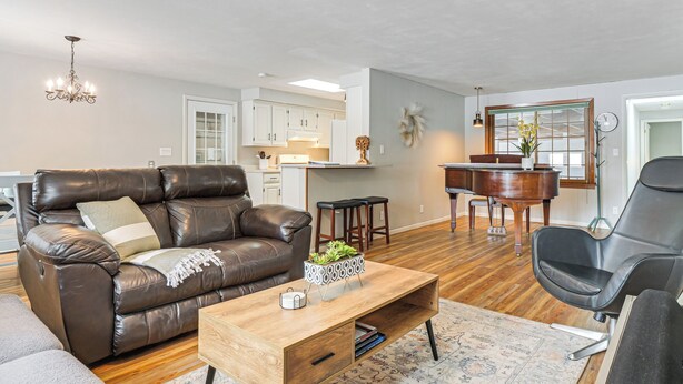 A living room with a brown leather sofa, a wooden coffee table, a black chair, and a piano. - Rice Lake Escape w/ Private Dock: 1 Mi to Main St (Rice Lake)