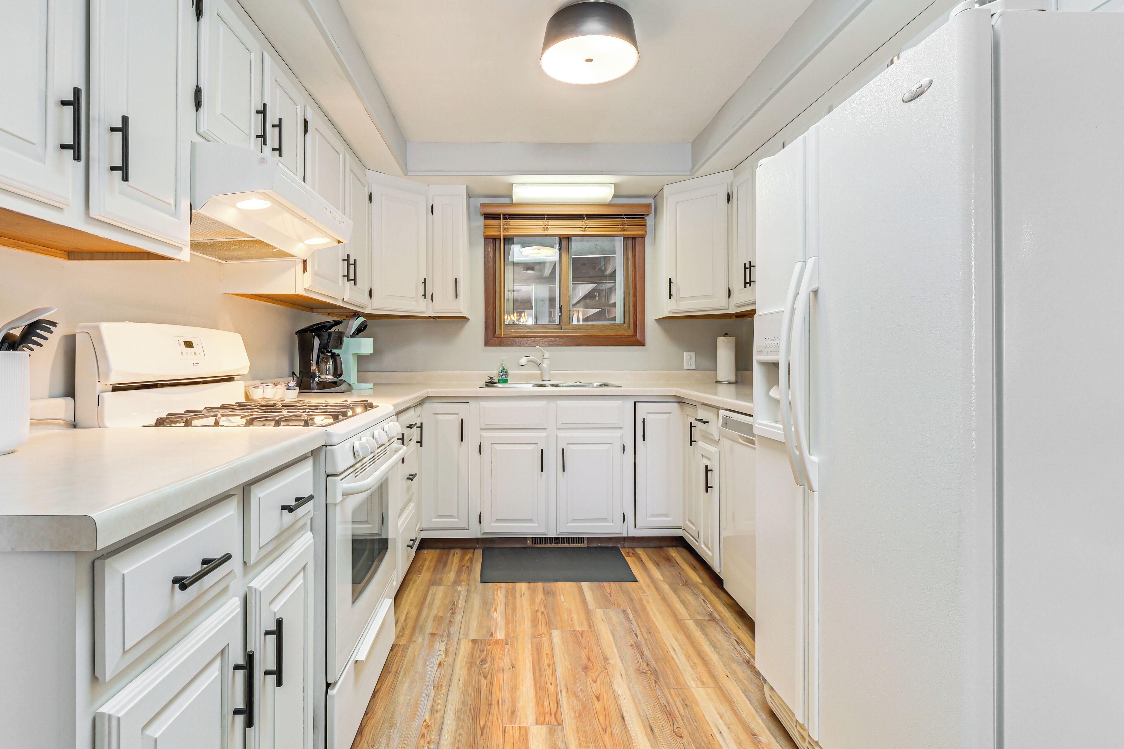 A modern kitchen with white cabinetry, a built-in oven, and a refrigerator.