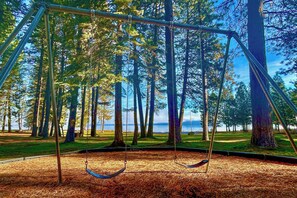 A swing set in a forested area with a view of a body of water. - Golf & Hike! Home in Lake Almanor West Community (Chester)