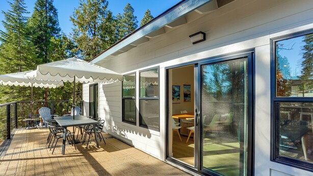 A modern house with a covered patio, sliding glass doors, and a view of the surrounding forest. - Golf & Hike! Home in Lake Almanor West Community (Chester)