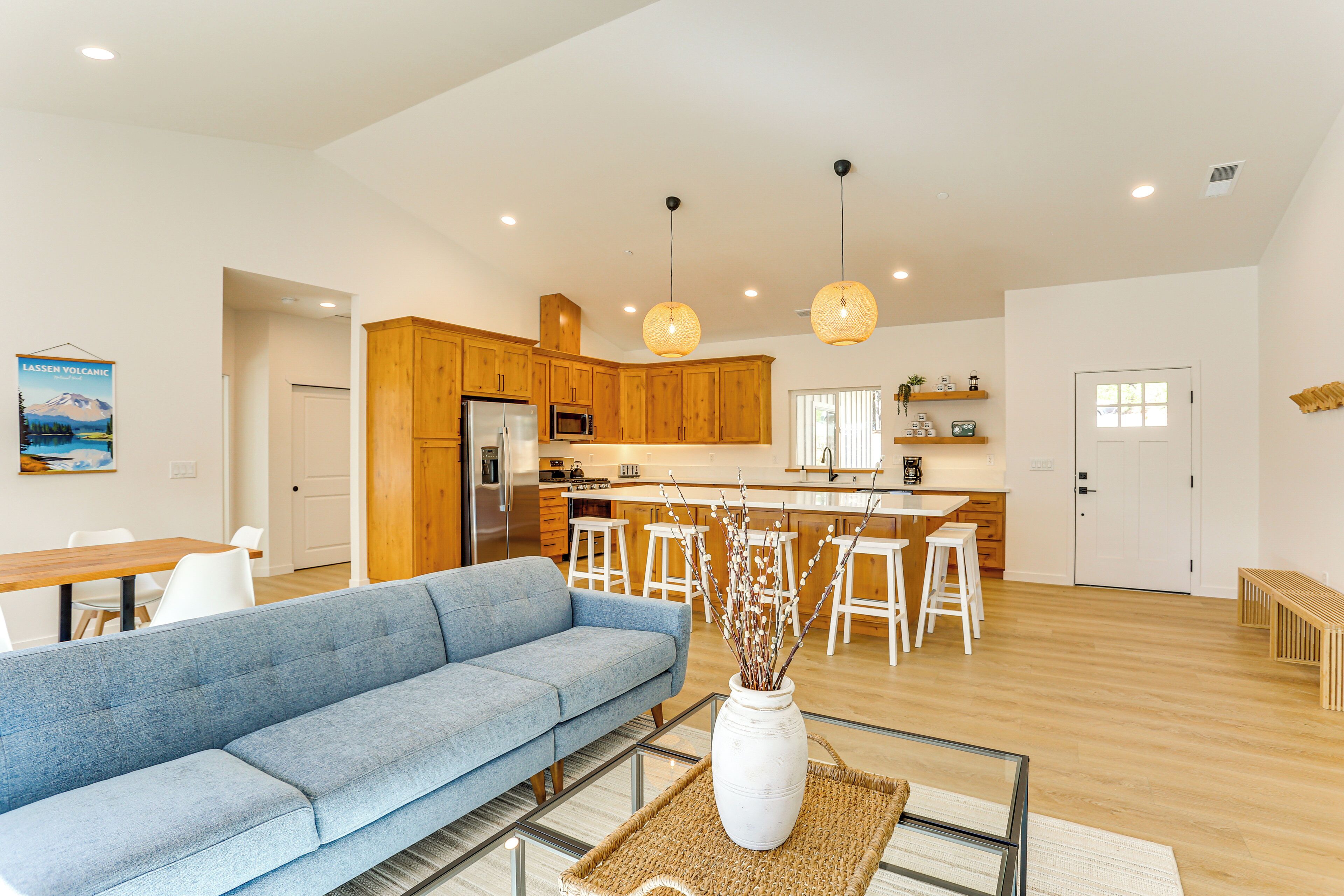 A modern kitchen with wooden cabinets, a central island, and pendant lighting.