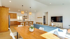 A modern kitchen with wooden cabinets, a dining area with a wooden table, white chairs, and pendant lighting. - Golf & Hike! Home in Lake Almanor West Community (Chester)
