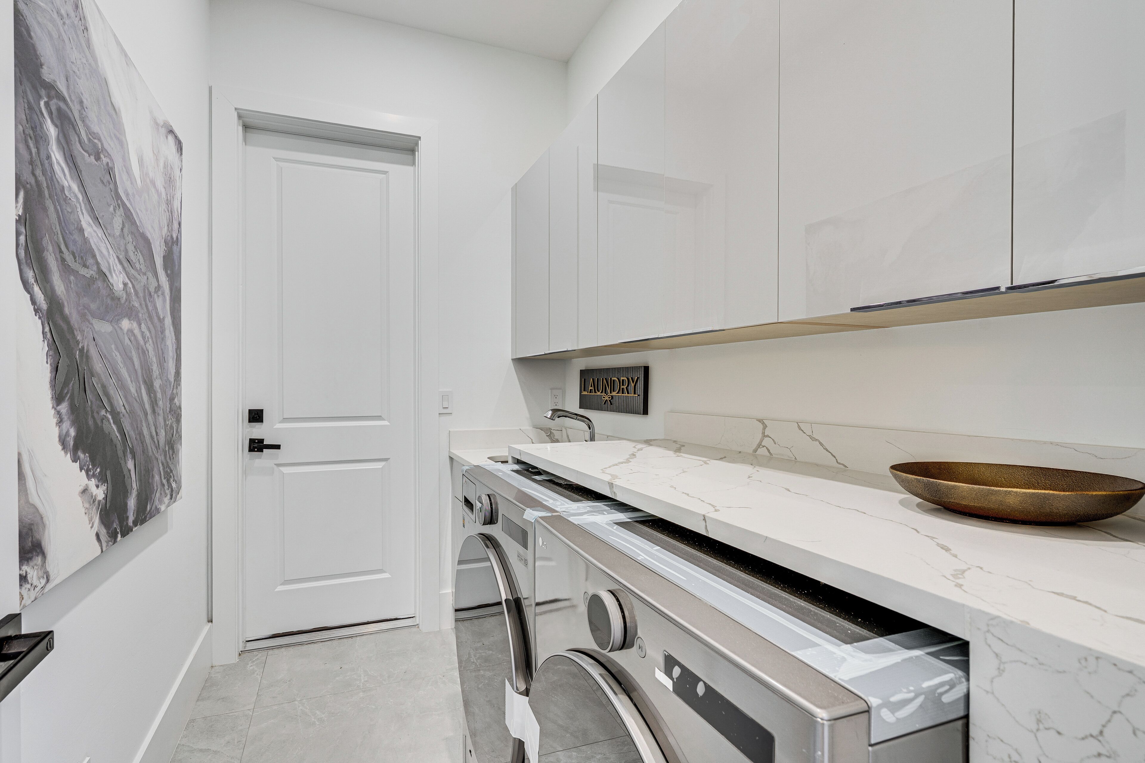 Een moderne keuken met witte kastjes, een marmeren aanrecht en een roestvrijstalen vaatwasser.