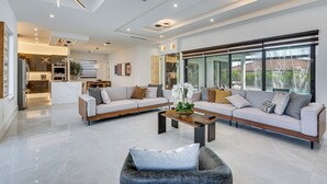 A modern living room with a sectional sofa, a coffee table, and a grey armchair. - Luxe Outdoor Space! Pet-friendly Cape Coral Home (Cape Coral)