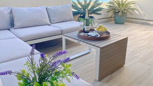 A modern outdoor seating area with a sofa, a wooden coffee table, and a potted plant. - Spacious 3-bedroom semi-detached house in kilometer 14 (La Manga del Mar Menor)