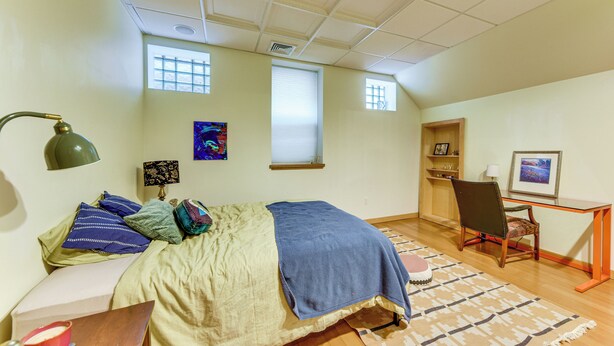 A bedroom with a bed, bedside table, lamp, chair, desk, and a window. - Long-term Stay in Milwaukee! Pet-friendly Condo (Milwaukee)