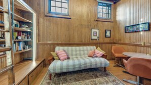 A cozy room with wooden paneling, a sofa with striped cushions, a small table, and a bookshelf filled with books and decorative items. - Long-term Stay in Milwaukee! Pet-friendly Condo (Milwaukee)