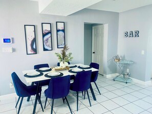 A dining area with a white table set for six, blue chairs, and framed artwork on the wall. - 
For family fun or a romantic escape close to sarasota and the area"s beaches (Bradenton)