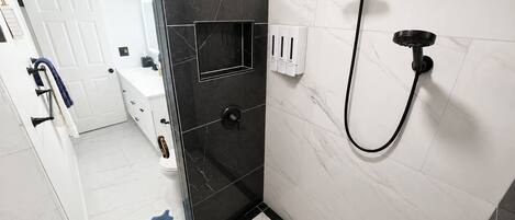 A modern bathroom with a shower, a toilet, and a sink.
