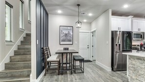 Eine moderne Küche mit einem Edelstahl-Kühlschrank, einer Mikrowelle und einem Essbereich mit Tisch und Stühlen.