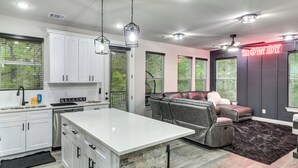 Eine moderne Küche mit weißen Schränken, einer zentralen Kochinsel und einem Essbereich mit grauem Sofa.