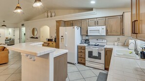A modern kitchen with white appliances, wooden cabinets, and pendant lighting. - Cute Home w/ Boat Parking, Monthly Specials (Lake Havasu City)
