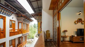Ein traditioneller Holzbalkon mit Tisch, Stuhl, Fernseher und einem Blumenvasen.