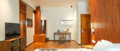 A hotel room with a bed, a TV, a desk with a chair, and wooden paneling.
