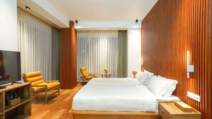 Ein Hotelzimmer mit einem großen Bett, Holzmöbeln, einem Fernseher und Blick auf die Stadt.