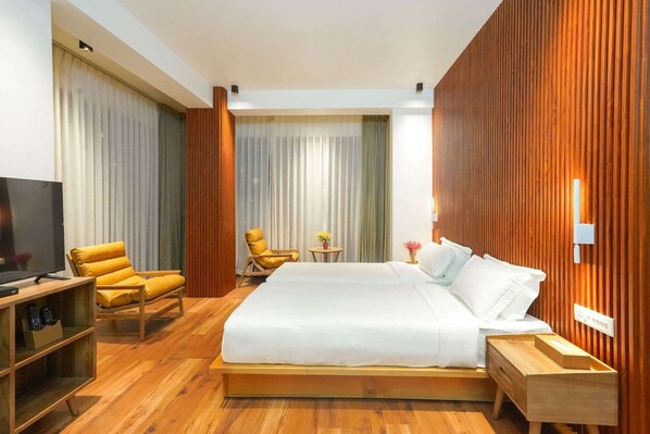 Une chambre d’hôtel avec un grand lit, des meubles en bois, une télévision et une vue sur la ville.