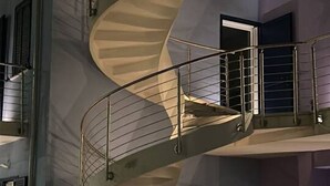 Uma escadaria em espiral com grades de metal e uma parede bege.
