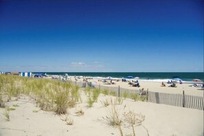 Ein Strand mit Sand, ein Holzzaun und ein klarer, blauer Himmel.