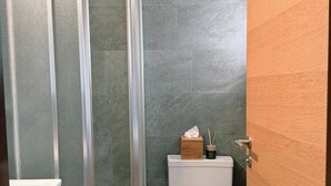 A modern bathroom with a glass shower enclosure, a toilet, and a wooden vanity. - Chalet Achat by Zermatt Premium Apartments (Zermatt)