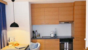 A modern kitchen with wooden cabinets, a black countertop, and a built-in oven. - Chalet Achat by Zermatt Premium Apartments (Zermatt)
