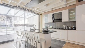 A modern kitchen with a central island, bar stools, and a large window providing natural light.