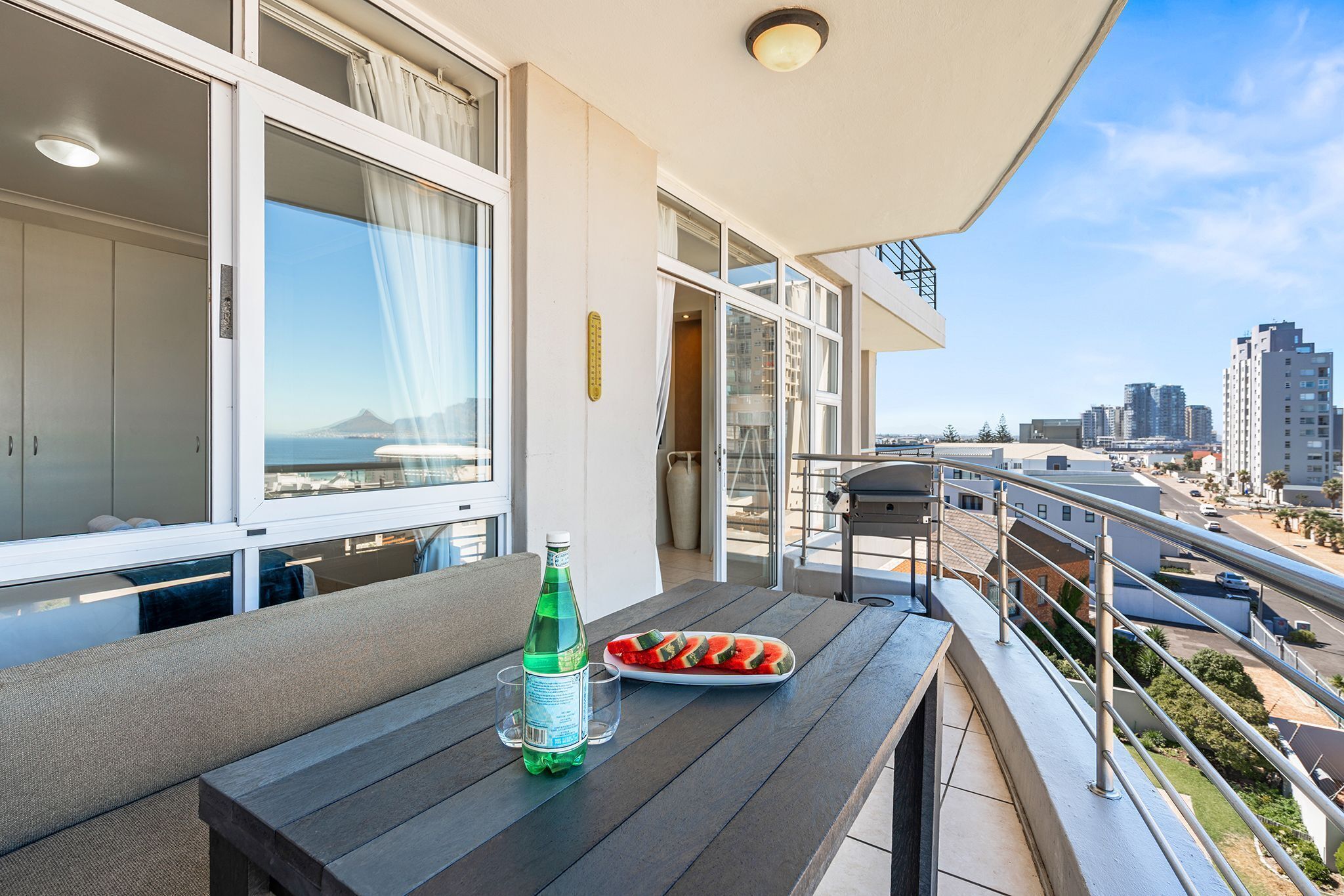 A balcony with a table, a bottle of water, and a watermelon slice.