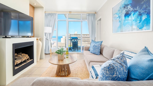 A modern living room with a fireplace, sofa, and a large TV. - Atlantic Terraces 19 (Cape Town)