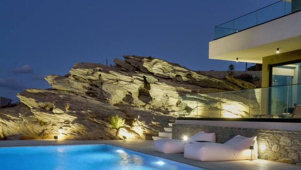 A modern pool with clear blue water, surrounded by stone walls and a rock formation. - New Luxury Villa w/ Private Pool, Spa & Sea Views! (Heraklion)